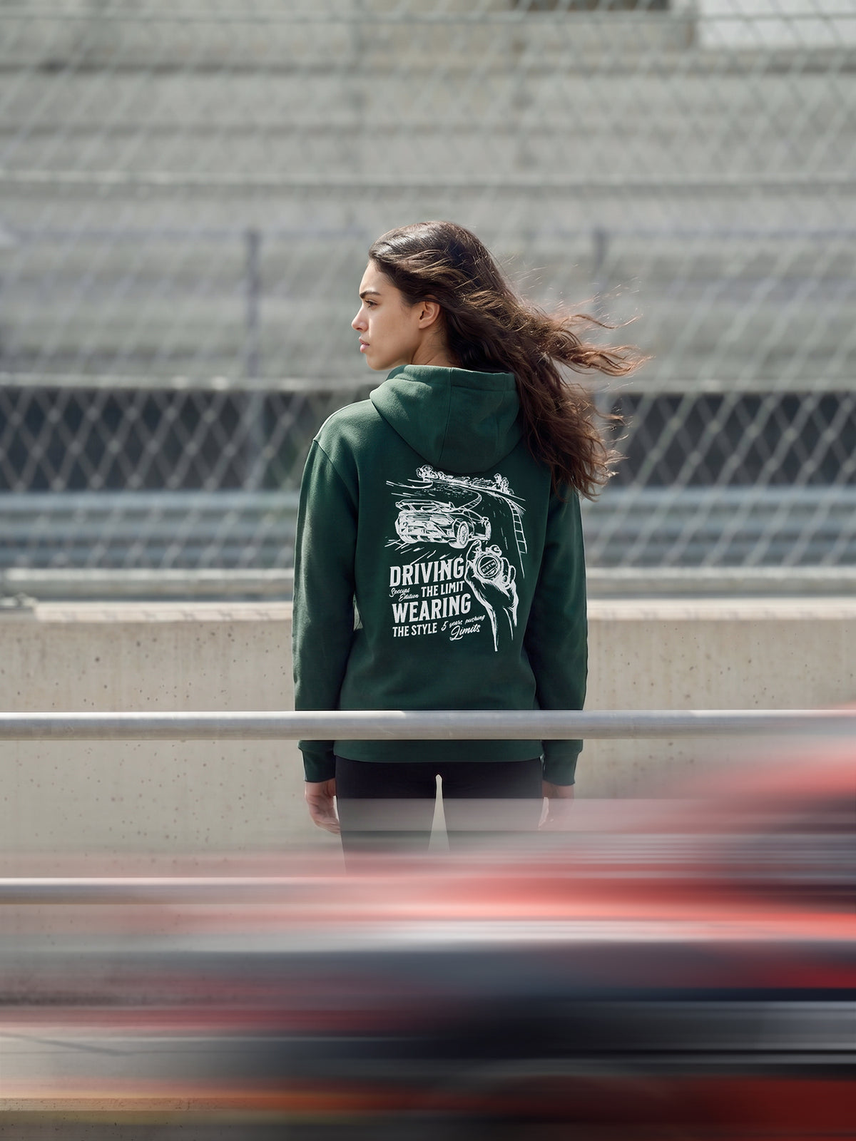Modell trägt den Driving the Limit Hoodie in Dunkelgrün mit weißen Siebdruck auf dem Rücken