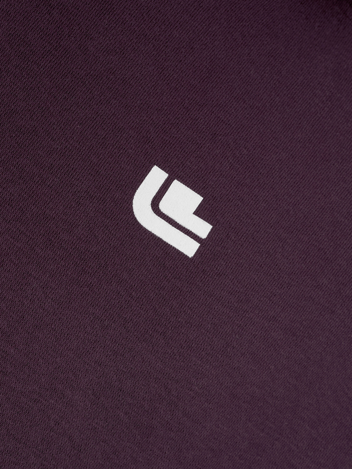 Detailaufnahme des weißen Brustlogos auf dem Driving the Limit Hoodie in Plum